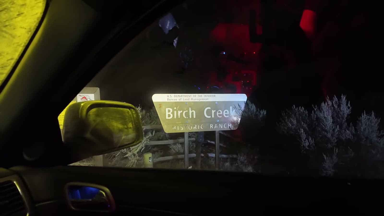 The Birch Creek sign lit up by headlights after dark