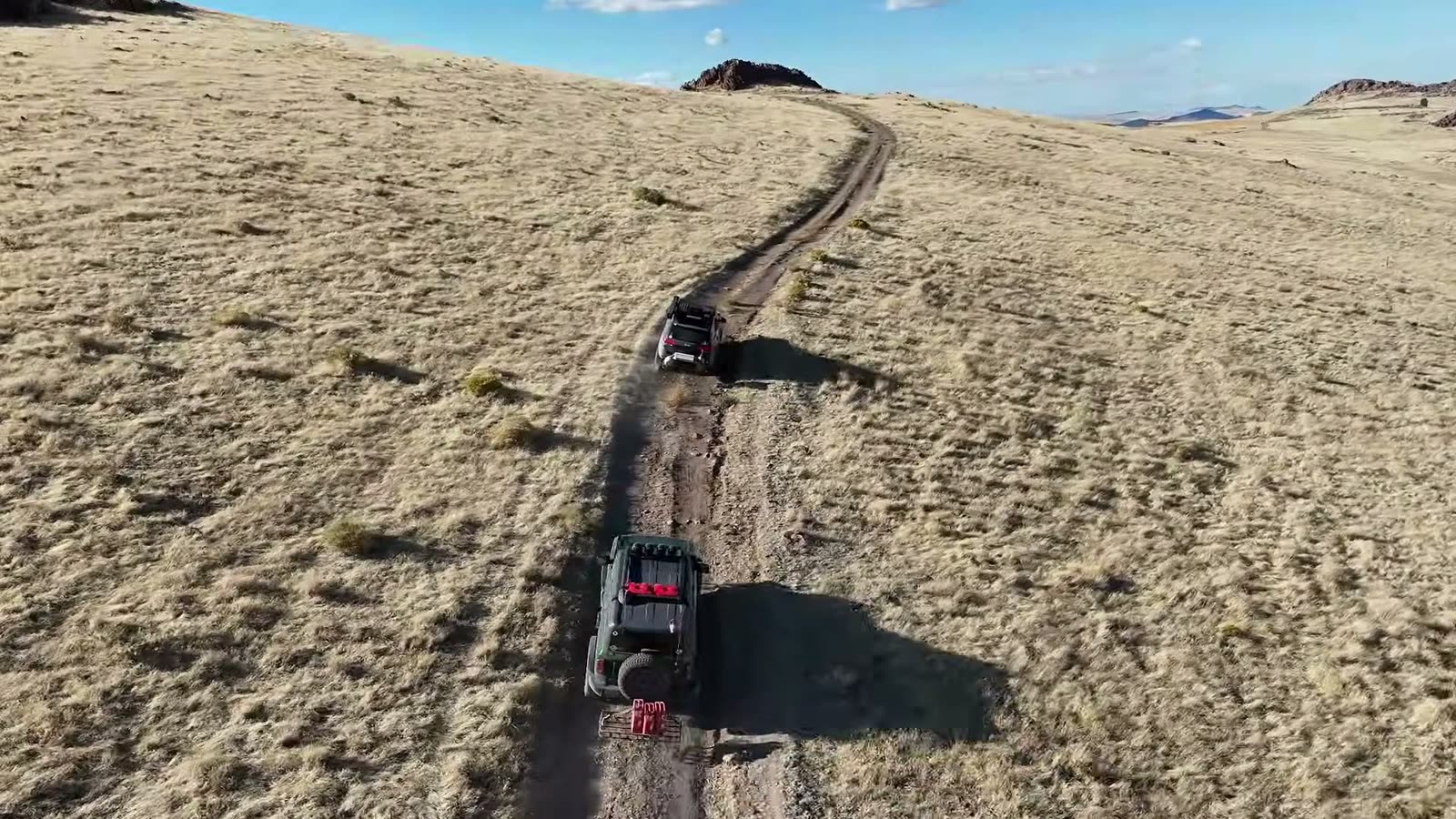 The convoy strung out along a two-track across golden hills